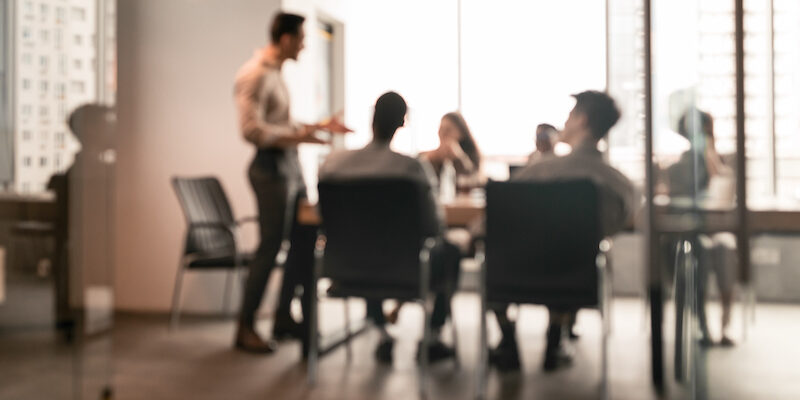 Colleagues having meeting in boardroom, businessman giving speech, blurred photo meeting
